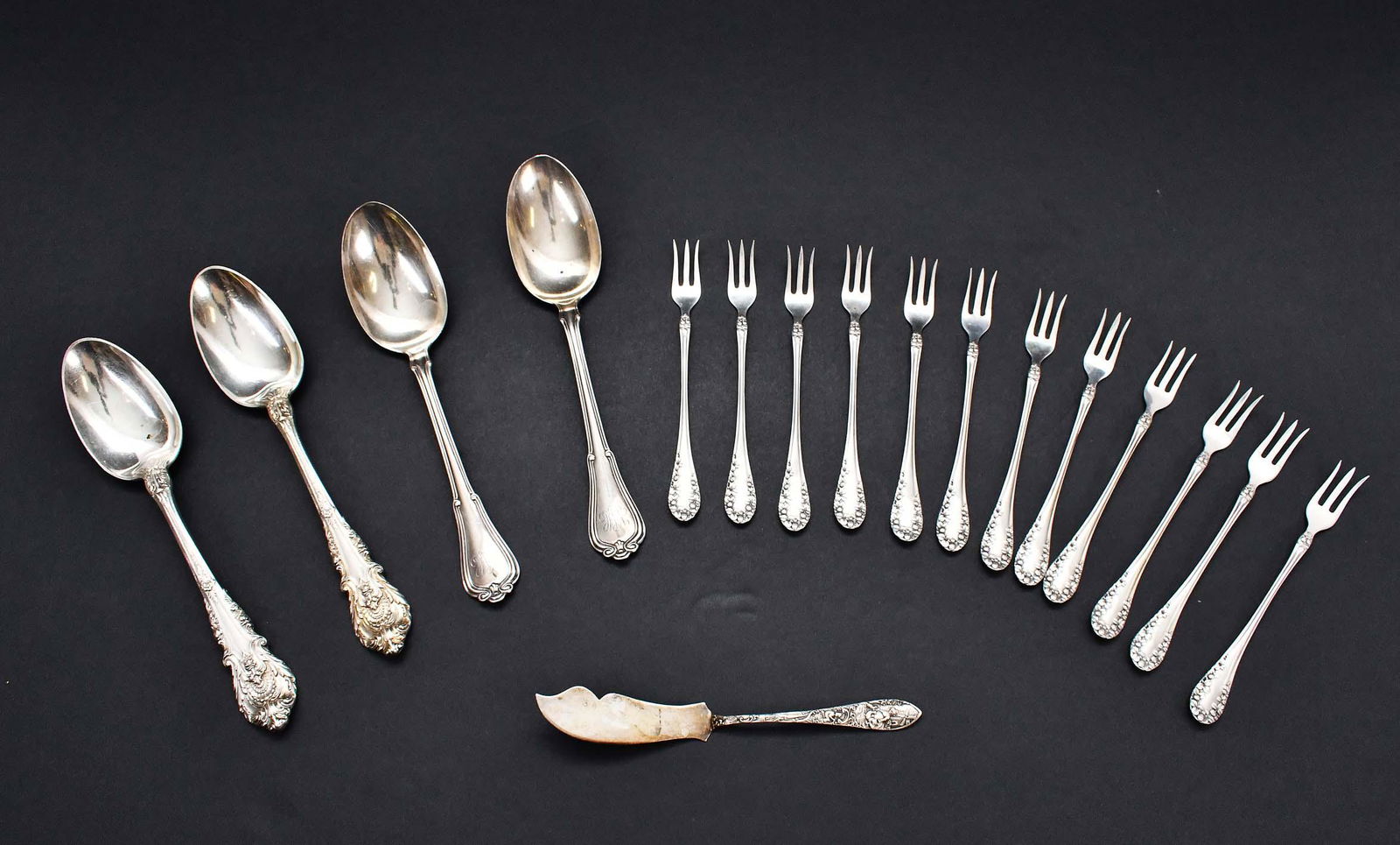 FOUR STERLING SERVING SPOONS & TWELVE COCKTAIL FORKS: Late 19th/Early 20th Century. American. The spoons marked. Comprised of a pair of Wallace Spoons and a Gorham pair, the forks chased with a pine cone and leaves. Together with a sterling butter spread