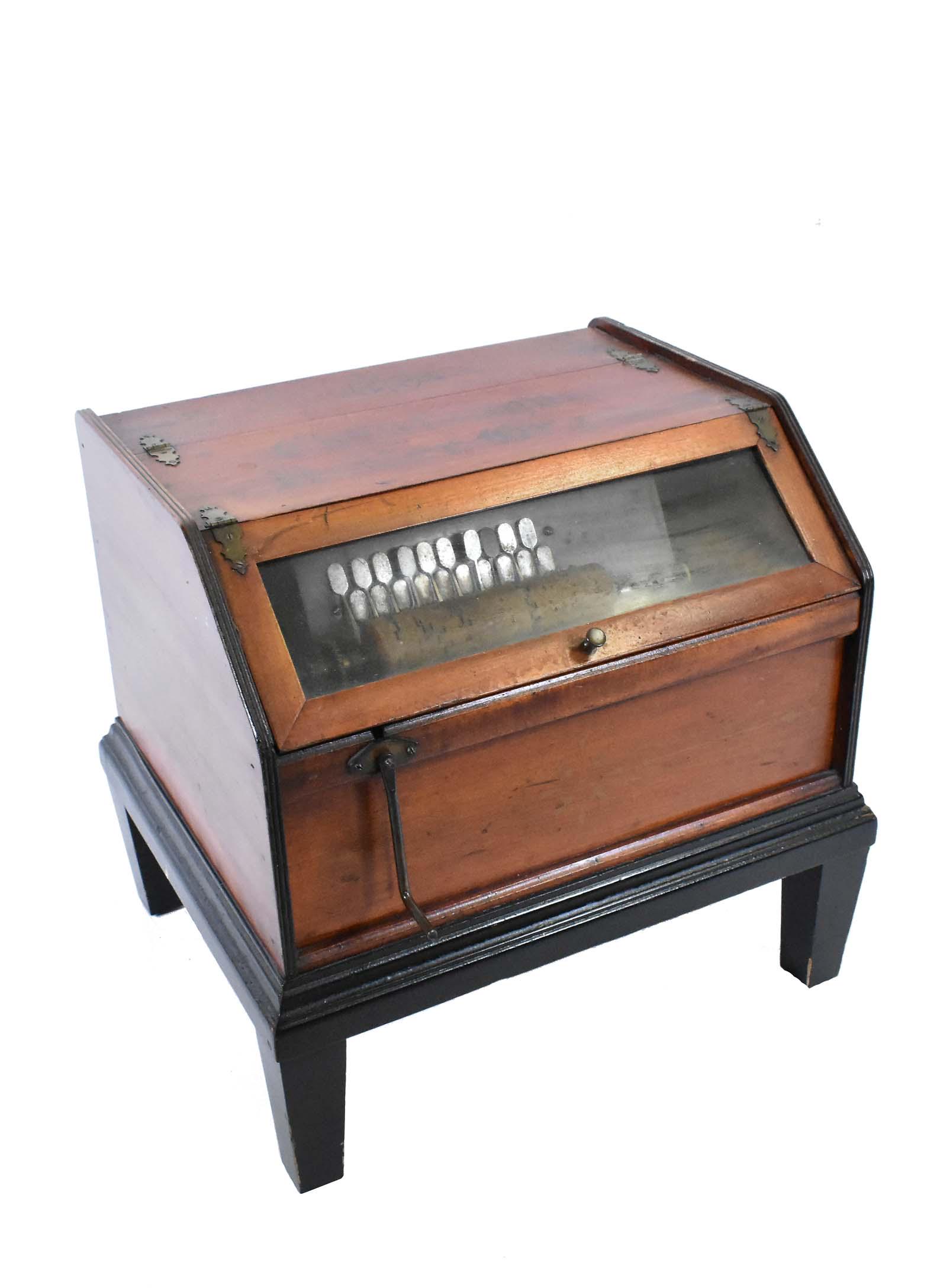 CHAUTAUQUA ROLLER ORGAN: 1890-1910. The twenty key mechanism engaged via a hand crank, with two cob rollers, in a gilt stenciled walnut case with a glazed panel, on an ebonized stand. Height 17 in. Width 18 in. Depth 15 in. (