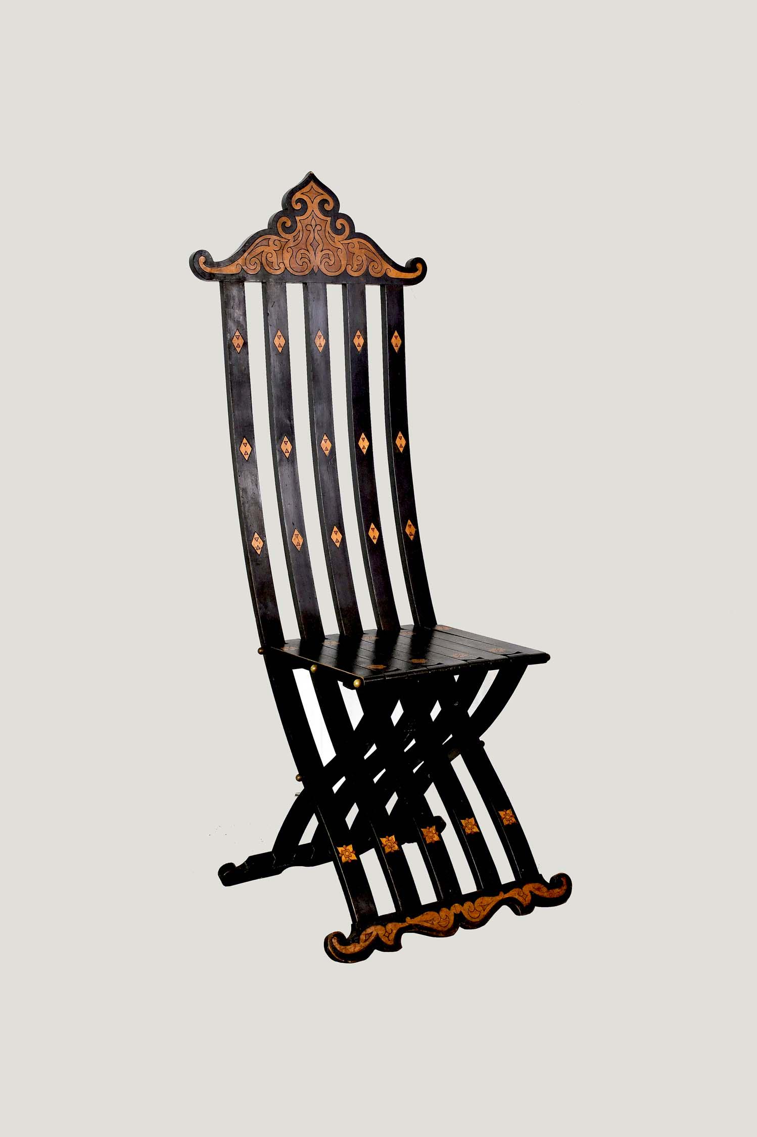 ITALIAN BAROQUE STYLE INLAID FOLDING SLAT CHAIR: Modern. The ebonized side chair with a crest and base decorated with various wood scrolling marquetry, the seat dotted with inlaid stylized flower heads.