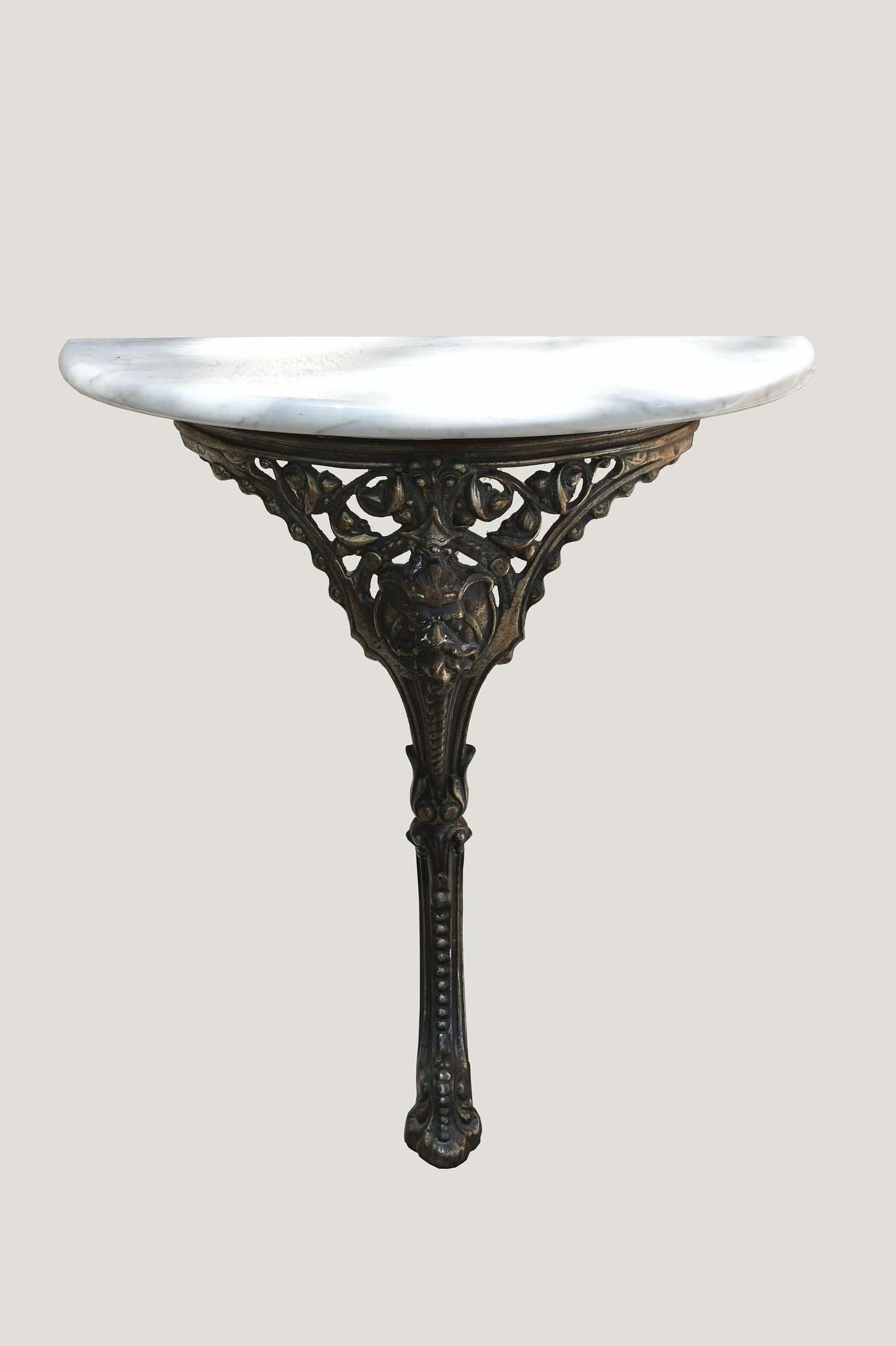 CONTINENTAL MARBLE AND POLISHED STEEL DEMILUNE CONSOLE: First Half 20th Century. The white marble top on a single cabriolet cast with a baroque masque.Width is 27 in., Depth 13 in., Height 27.5 in.