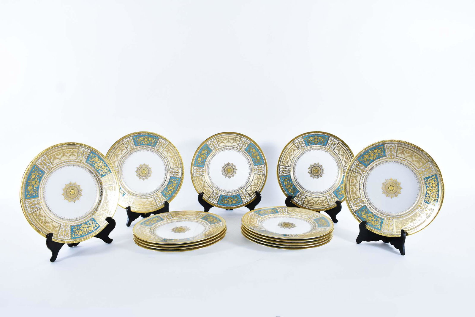 12 FINE MINTON PORCELAIN SERVICE PLATES: Mid 20th Century. Printed Minton wreath icon, also impressed and painted marks in red and gold. In a Florentine style. The borders decorated with arabesques and scrolls in raised gilt, on alternating 