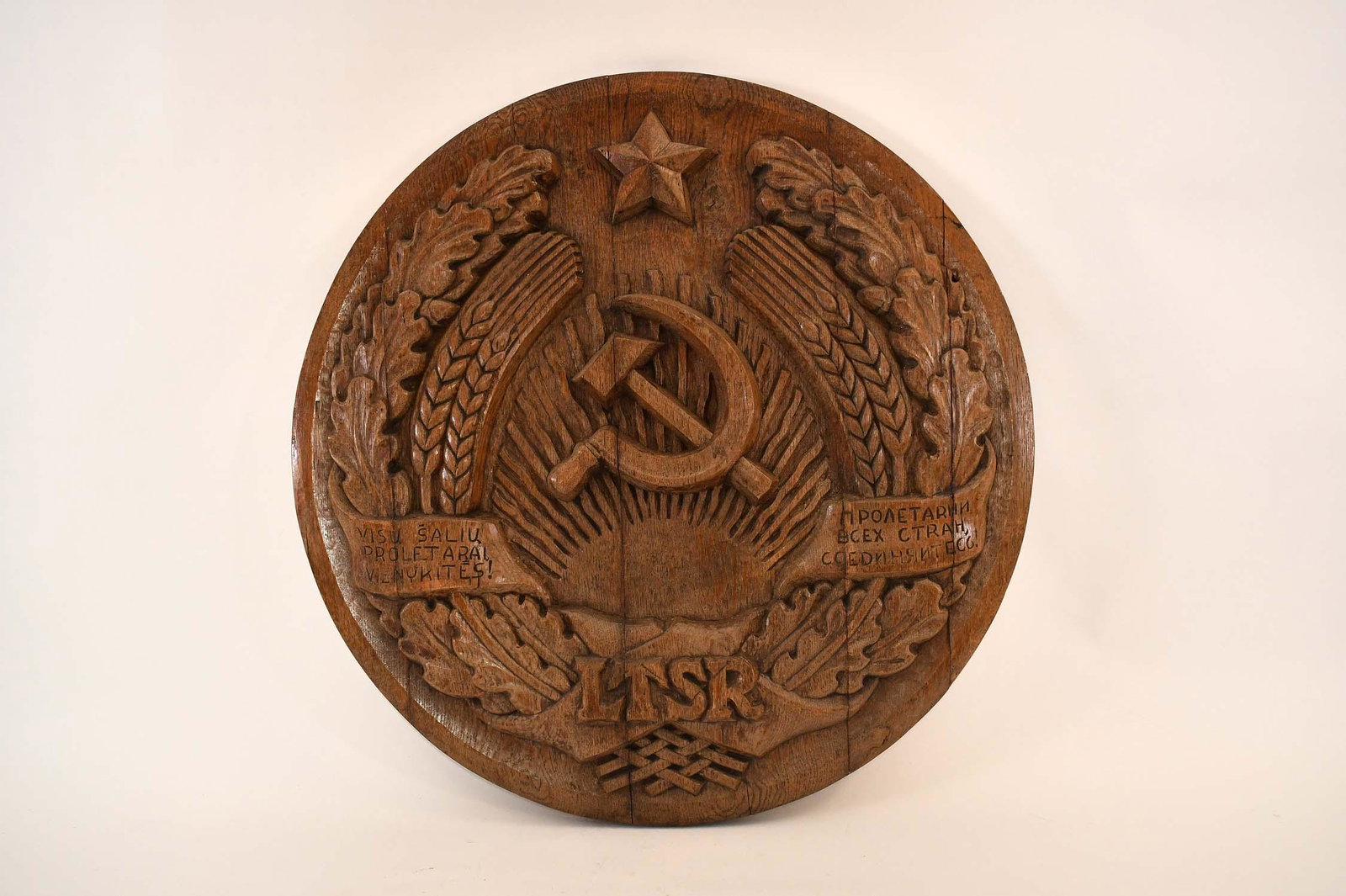 LITHUANIAN SOVIET SOCIALIST REPUBLIC STATE EMBLEM: Mid 20th Century. The large oak roundel carved with a hammer and cycle centered by wheat sheaves and oak leaves, with a banner inscribed LTSR, with flanking text in Cyrillic, the whole with an excelle