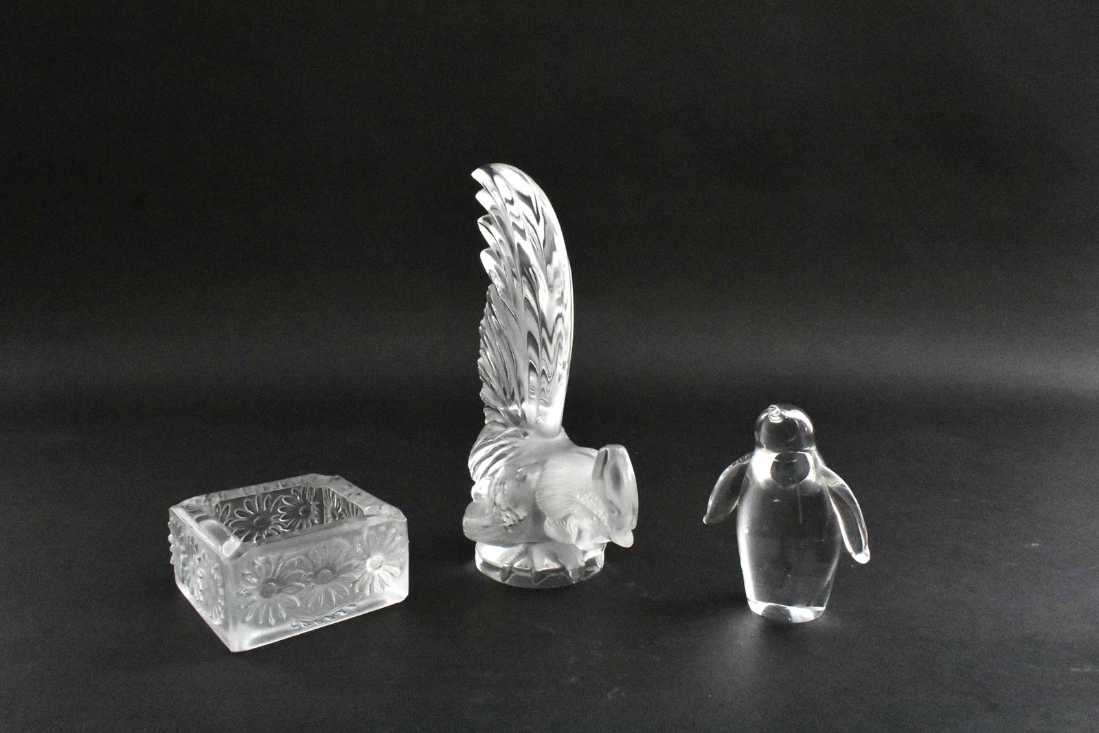 LALIQUE COLORLESS GLASS ROOSTER: Modern. Signed in block letters LALIQUE FRANCE. Together with a frosted glass ash receiver and a colorless glass penguin. (3 pcs) Rooster Height 8 in. Width 5.5 in. Provenance: The Haggstrom Trust, Ju