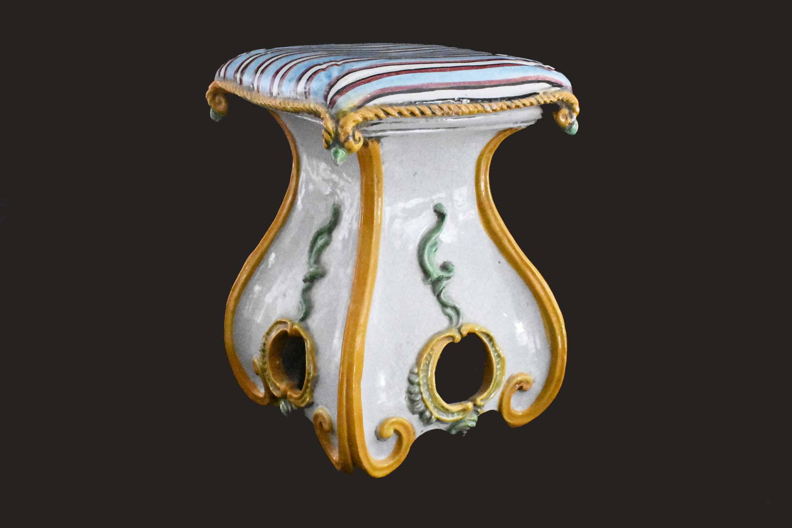ITALIAN MAJOLICA GLAZED TERRA COTTA LOW STOOL: Modern. Modeled as a cushion atop a scrolled pedestal. Height 17 in. Width 12.5 square.