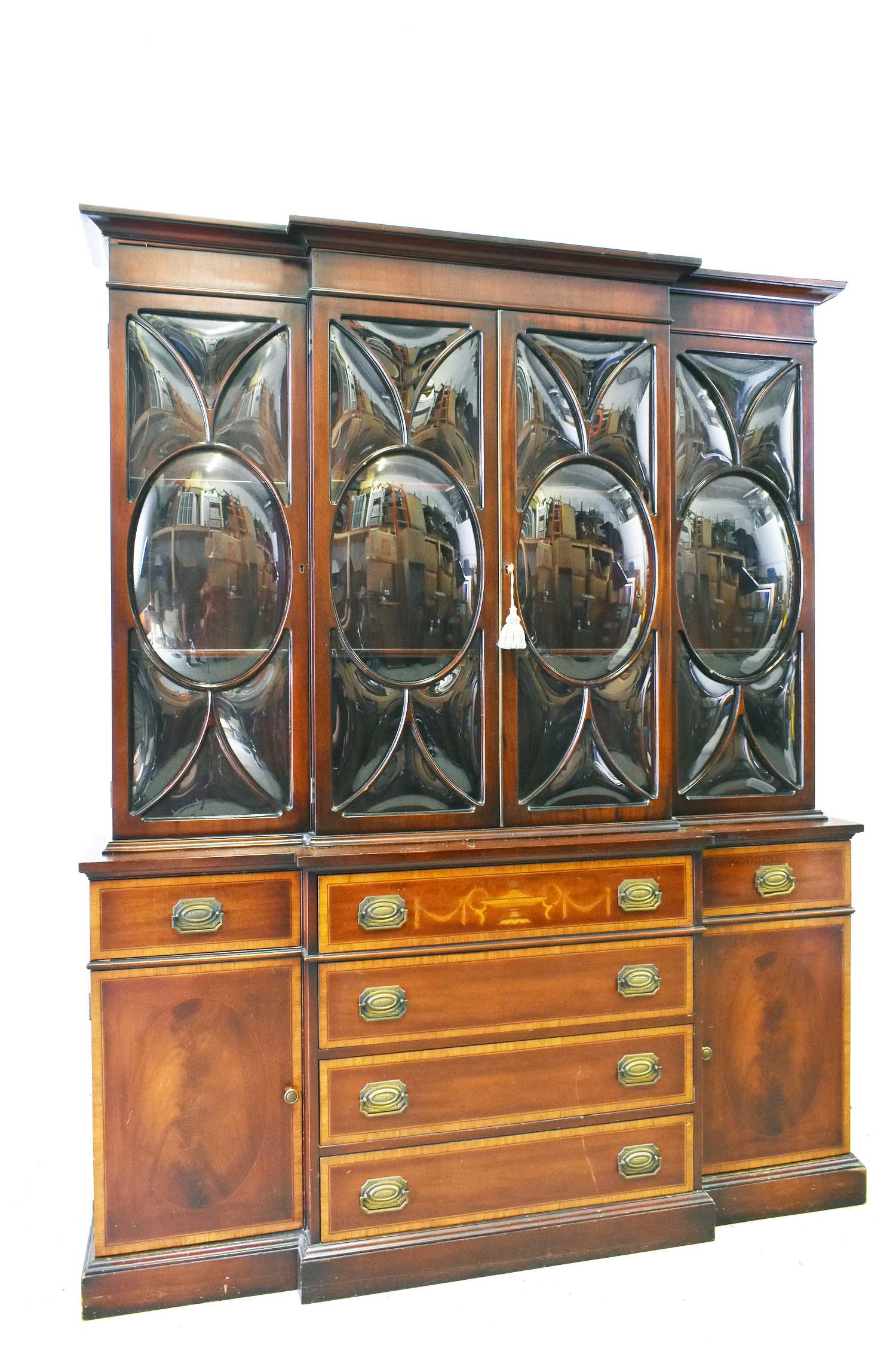 GEORGE III INLAID MAHOGANY BREAKFRONT BOOKCASE: The upper section with four doors each with convex glazed panels opening to shelves, the conforming lower part with a fitted secretary drawer, flanked by satinwood cross-banded small drawers above a c