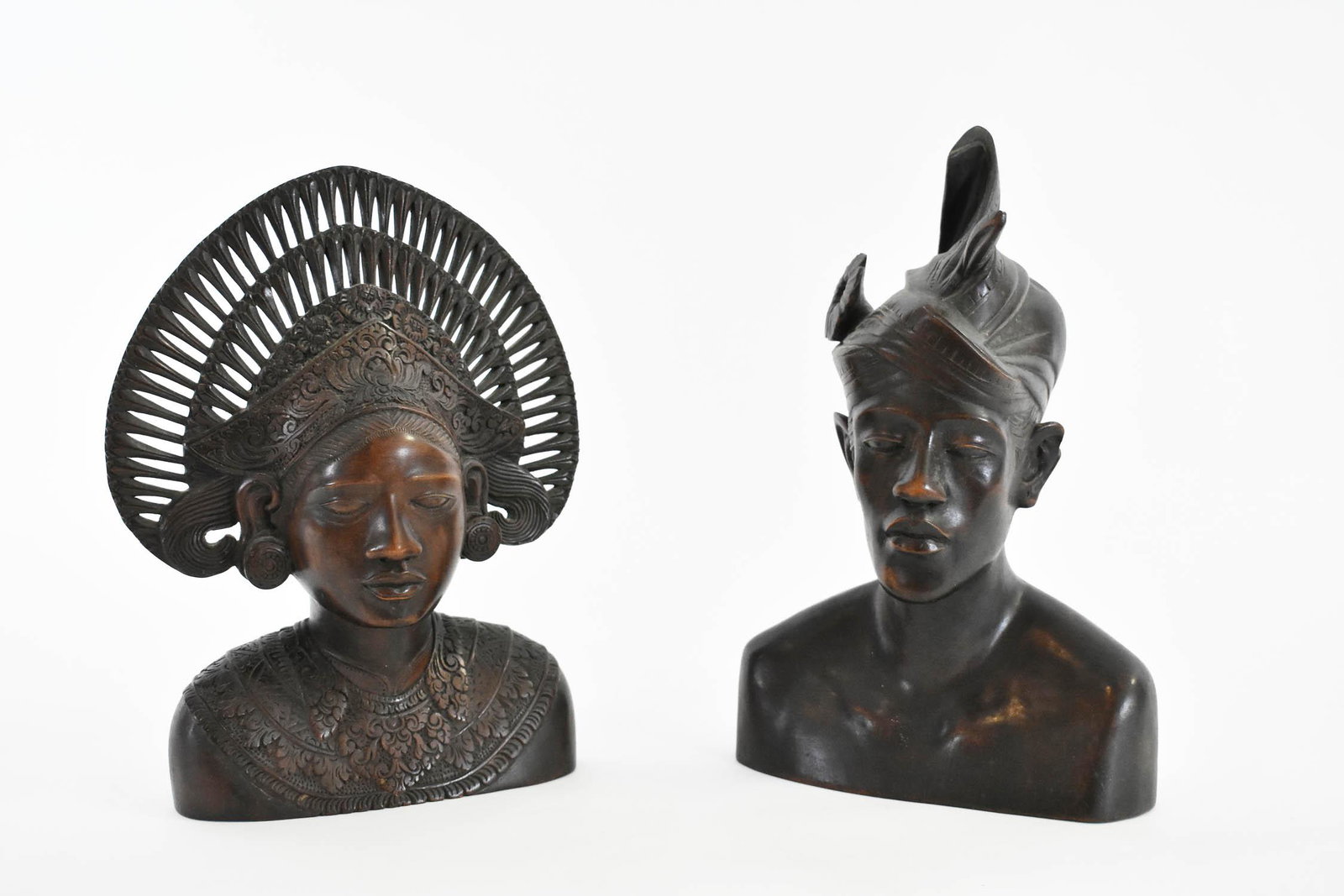 PAIR OF INDONESIAN WOOD BUSTS OF A MALE AND FEMALE: Modern. Each with an elaborate headdress. Heights 12 in., 11 in. Provenance: Property of The Haggstrom Trust, Jupiter, FL