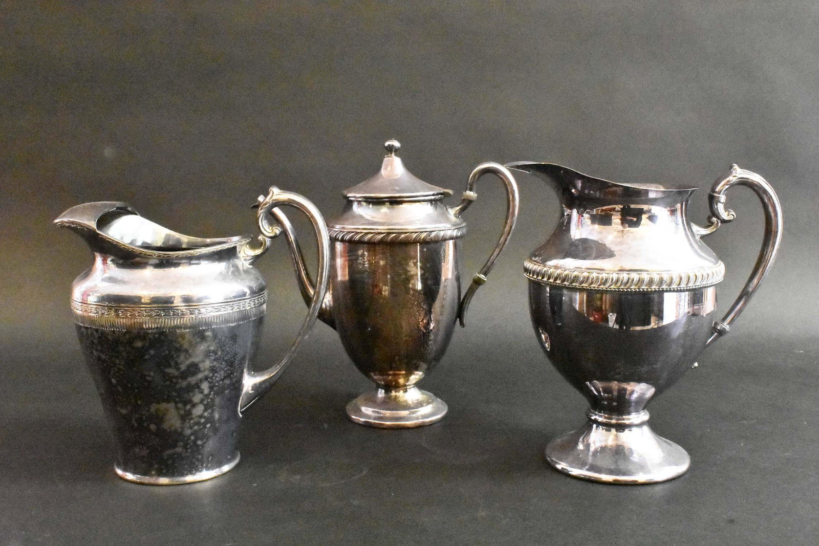 THREE SILVER PLATE PITCHERS: Circa 1880 go 1920. All marked, one impressed Rogers Silver Co. All with loop handles. Heights 8.5 to 10.5 in. Provenance: Property of The Haggstrom Trust, Jupiter, FL