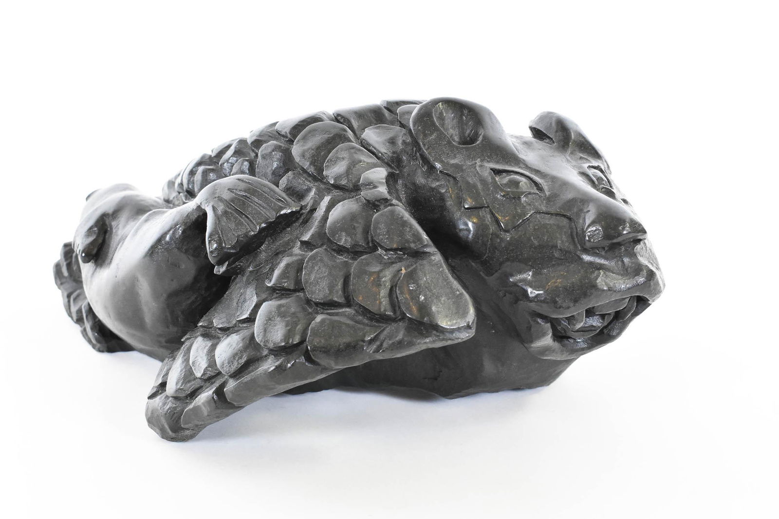 BART HANNA, RARE INUIT STONE MYTHICAL CREATURE: Signed, B. (Bart) Hanna, Igoolik, NWT. The animal with a cat-like face, the body and flippers carved as overlapping scales, a large seal by its side. Height 5.5 in. Width 9 in. Depth 14.5 in. Provena