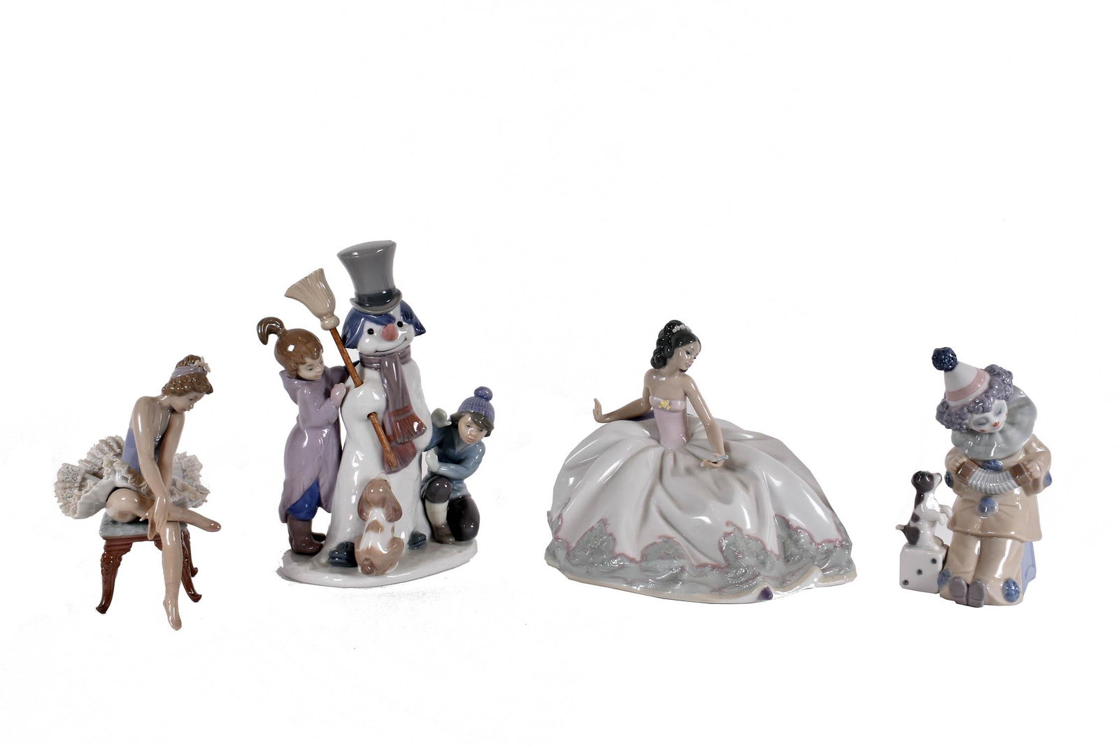 FOUR LLADRO PORCELAIN FIGURES: Each marked on the underside. Comprising: a clown with a puppy, a snowman with two children and their dog, a ballerina seated atop a stool and a young woman in a ball gown. Heights 6 in., 8 in., 5.5 i
