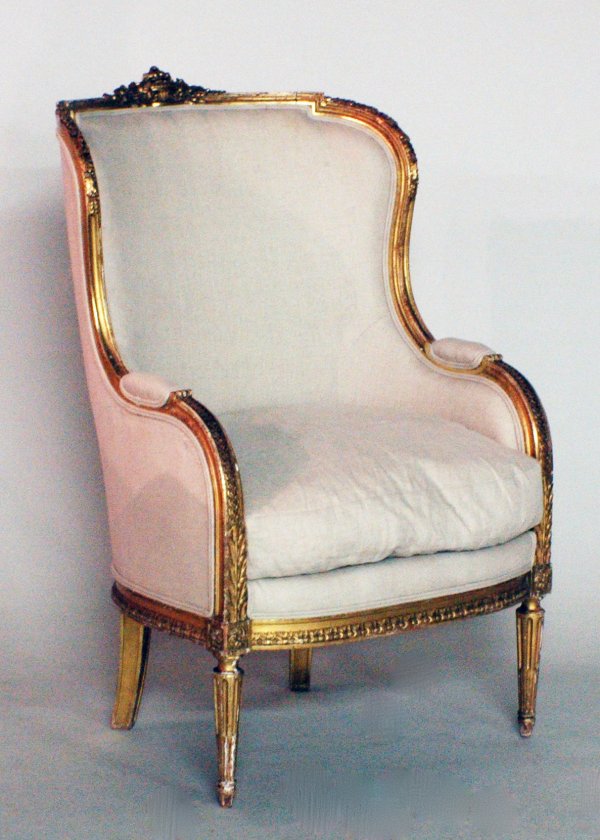 LOUIS XVI STYLE CARVED AND GILTWOOD BERGERE: LOUIS XVI STYLE CARVED AND GILTWOOD BERGERE French. 19th Century. The curved top rail centered by a flower filled basket above the padded back continuing to form arms, the seat with loose cushion rais