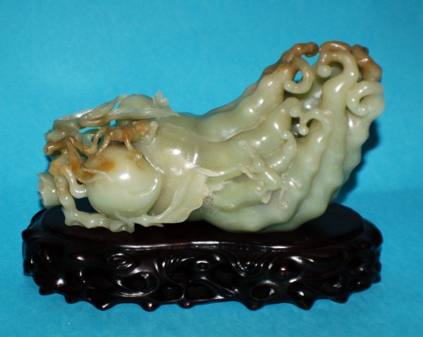 UNUSUAL YELLOW JADE CITRON: UNUSUAL YELLOW JADE CITRON Chinese. The fruit and roots also known as Buddha's hand pierced and carved with monkeys. Length 6 1/4". With carved wood stand. (4000/5000)