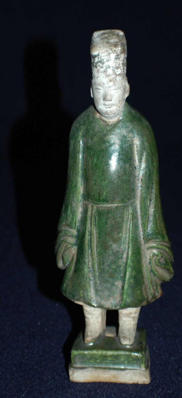 GREEN GLAZED POTTERY FIGURE OF A STANDING OFFICIAL: GREEN GLAZED POTTERY FIGURE OF A STANDING OFFICIAL Chinese. Song Dynasty. 960-1279. Wearing a long coat and peaked cap, raised on a square base. Height 8". Provenance: Kawabun & Co., Japan. June 4, 19