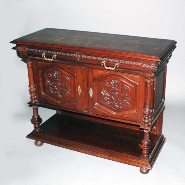 CARVED OAK SIDEBOARD: French. Circa 1890. The rectangular parquetry top above two frieze drawers and two carved cupboard doors flanked by reeded columns and a platform stretcher, raised on bun feet. Height 40 3/4". Width 4