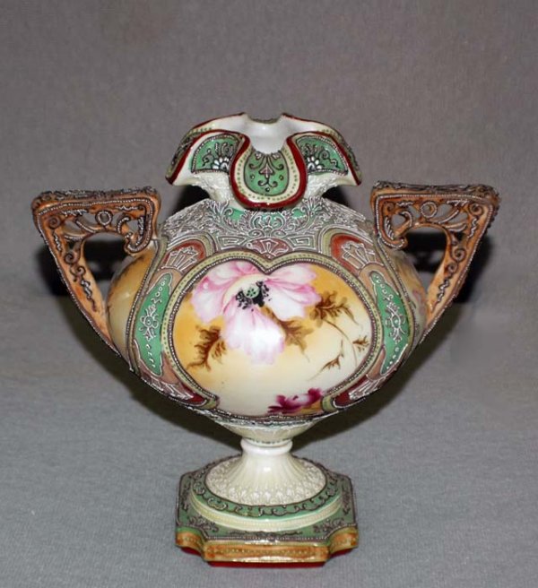 NIPPON PORCELAIN VASE: Japanese. Early 20th Century. Of bulbous shape with garlic mouth and pierced handles, raised on a pedestal base. Height 9". (200/300)
