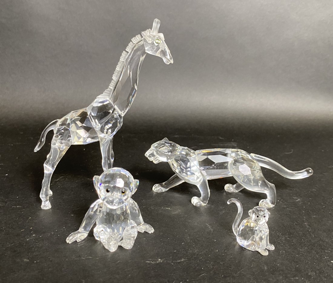 FOUR SWAROVSKI AFRICAN PLAINS ANIMALS: Signed. Comprising giraffe, a lioness and two monkeys. Height of giraffe 5.25 in. Width of lioness 5.75 in.