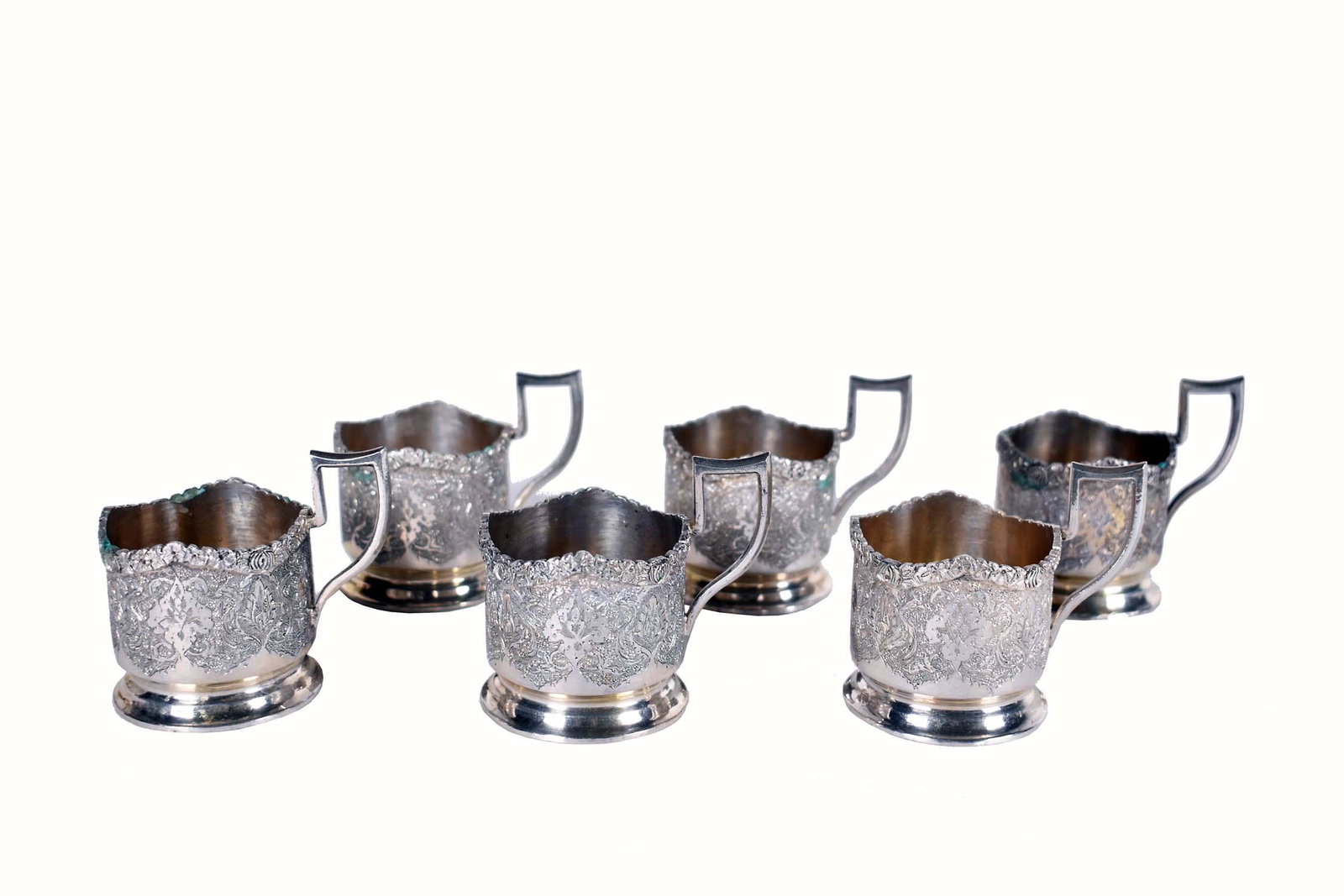 SET OF SIX PERSIAN SILVER RAMEKIN CUPS: Early 20th Century. Persian Hallmarks. En suite with the prior lot, sugar bowl and tongs. Each cylindrical cup with a pistol handle, chased allover with foliage, lack liners. 10.8 troy oz. Height 2.75