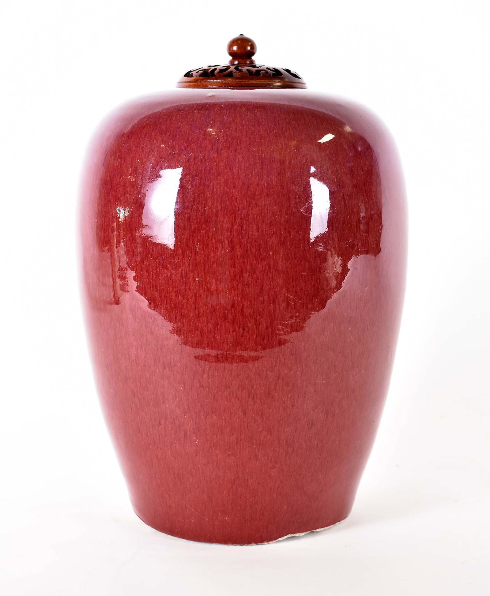 CHINESE SANG DE BOUEF PORCELAIN COVERED JAR: The ovoid vessel with a carved wood lid. Height 13 in. Diameter at shoulder 8 in.