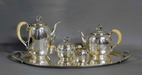 FIVE PIECE HAND HAMMERED STERLING SILVER TEA AND C: Danish. Post World War II. Maker: Holger Rasmussen. Comprising: tea pot, coffee pot, covered sugar bowl, creamer and tray. Each with ivory handle, excluding tray. (110 oz) (3000/5000)