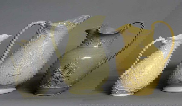 GROUP OF THREE ART POTTERY JUGS: English. Comprising: Spode molded with cherubs, height 10", Bennington molded with sheaf of wheat, height 10 3/4" and the last with molded registration mark on the underside and with four panels title