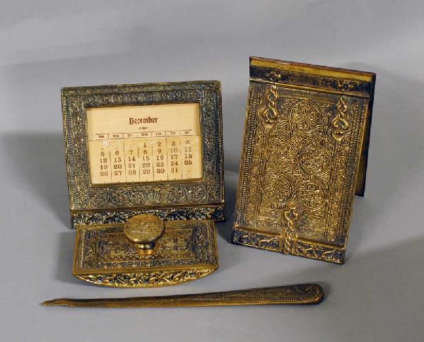 4 PIECE TIFFANY STUDIOS GILT BRONZE PART DESK SET: American. 1901-1920. In the "Venetian" pattern. Comprising: note pad holder, calendar, rocker blotter and letter opener. (Cond: letter opener tip bent) (1000/1500)