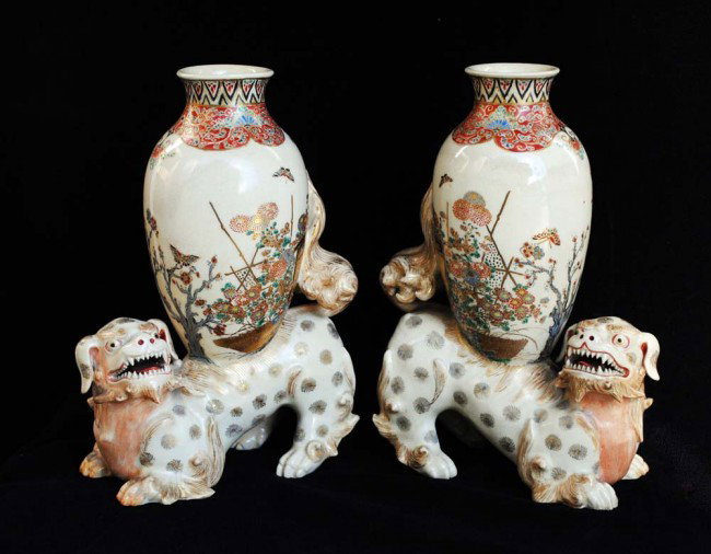 PAIR OF SATSUMA POTTERY FU DOG VASES: Japanese. Meiji-Period. Late 19th Century. Each modeled as a fu dog with open mouth supporting an ovoid form vase decorated with blossoming branches and kiku. Height 8 5/8". (1000/1500)