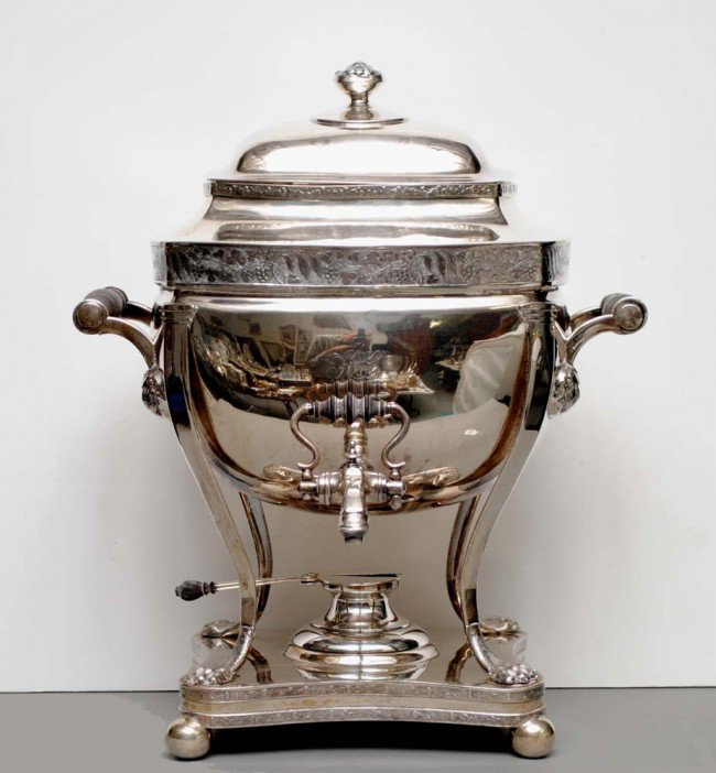 GEORGIAN SHEFFIELD PLATED TEA URN: English. 19th Century. With wooden handles ending in lion mask terminals, raised on hoofed feet supported by a shaped platform on ball supports. Height 14 ¾". (700/900)
