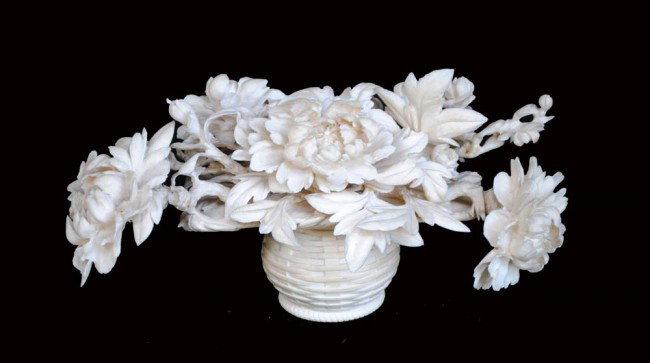 CARVED IVORY FLOWER BASKET: Japanese. 20th Century. In the shape of a woven straw basket containing a bouquet of chrysanthemums. Height 5". Width 9 5/8". (Cond: minor losses and restoration) (400/500) (NOTE: INTERNATIONAL SHIPPI