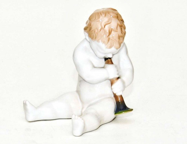 ROSENTHAL PORCELAIN FIGURE OF A PUTTO: German. 20th Century. Printed factory mark, impressed Model No. 997 and impressed designer E. Otto. The seated child playing a musical instrument. Height 5". (100/150)