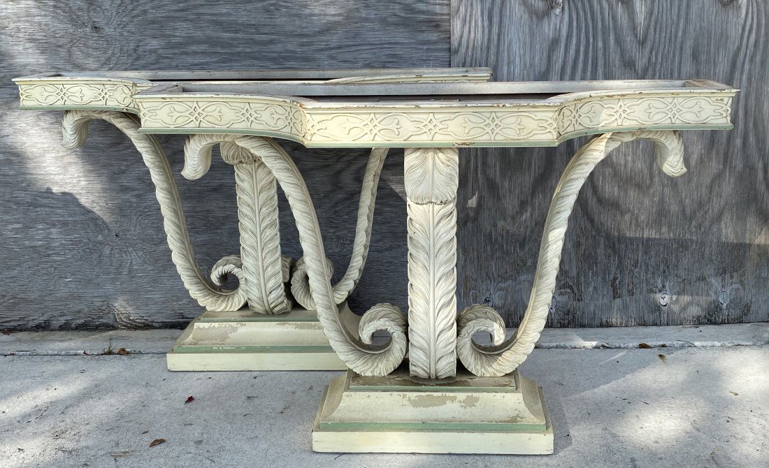 PAIR OF GEORGE III PAINTED MARBLE TOP CONSOLES: Mid-20th Century. The shaped black marble tops over a carved frieze, on three feather-carved supports, on a plinth, painted cream with green highlights. (Cond: both marbles repaired)Height 33 in, widt