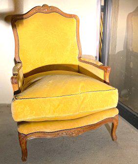 LOUIS XV STYLE BEECHWOOD BERGERE A LA REINE: Circa 1750. The shaped back with a cresting carved with foliage, with molded padded arms, the molded rail with foliage, on cabriole legs with flowers at the knee.