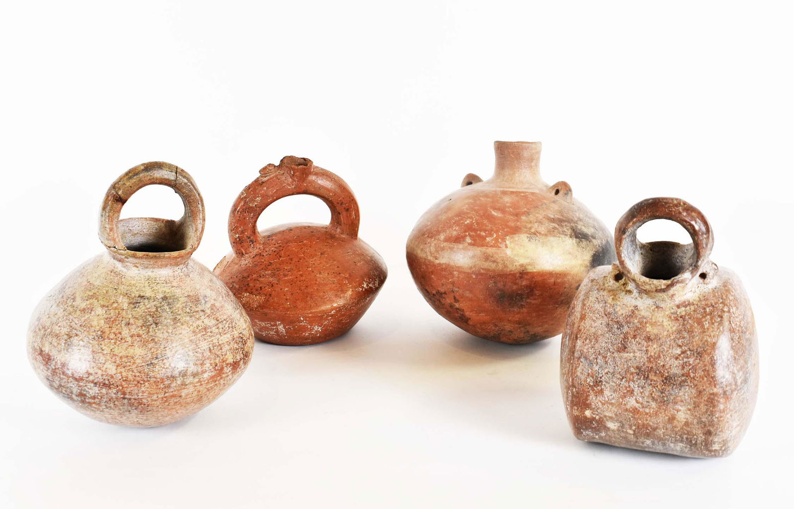 FOUR PRE-COLUMBIAN POTTERY VESSELS: One of drum shape, a spherical example, and two of slightly flattened spherical form. Heights 7 in. to 8 in.