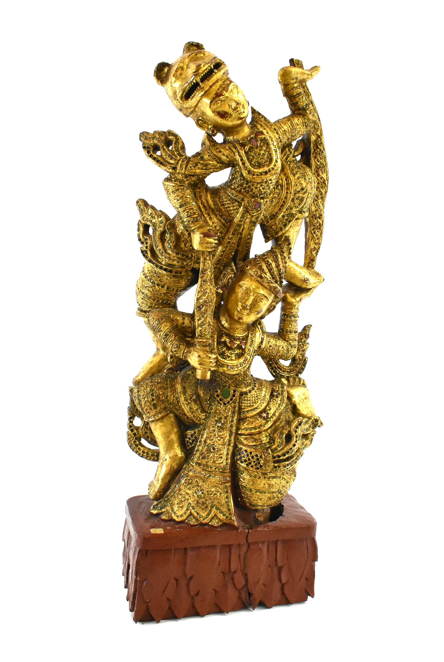 THAI CARVED AND GILT LACQUERED WOOD FIGURAL GROUP: Early to mid-20th Century. Depicting two female dancers, one atop the other, each elaborately dressed, the upper with a tiger mask, highlighted with colorful inlaid sequence, on a red lacquered base. 
