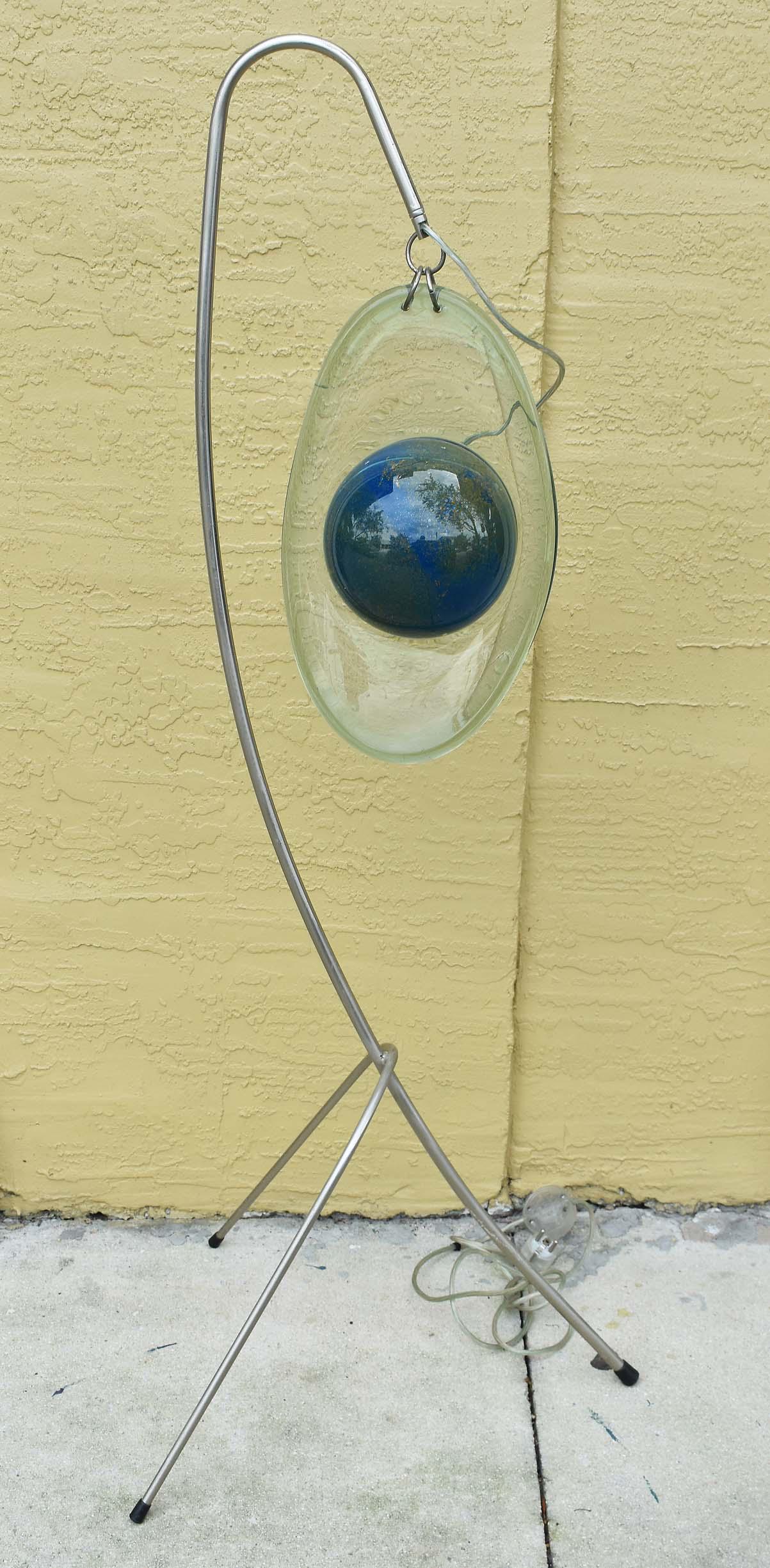 CONTEMPORARY GLASS FLOOR LAMP: Designed by Tzouros Ypsilantis, in his Atelier in Greece. Fitted with a pendant in the form of a blue glass orb within an elliptical colorless halo, decorated internally with gilt flakes, on a metal s