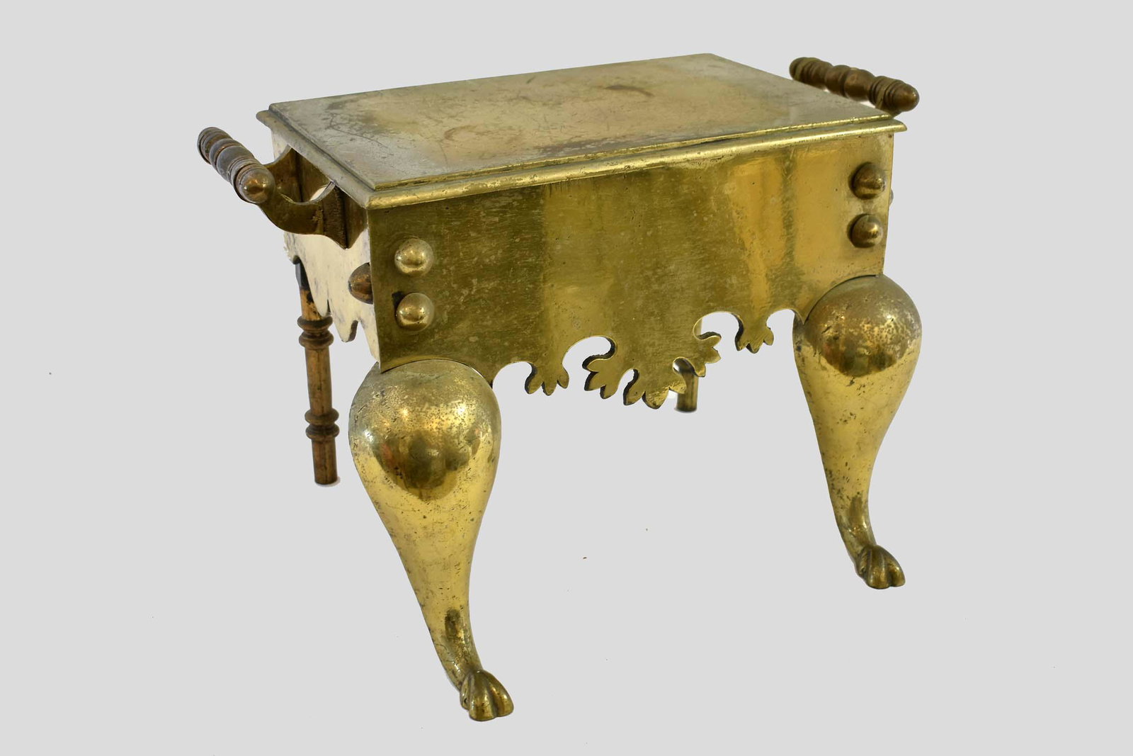 ANTIQUE BRASS TRIVET: 18th/19th Century. Typical in form, with handles at the sides, on bulging cabriole legs, centering a shaped skirt, ending in stylized paw feet. Height 12 in. Width 18 in. Depth 11 in.