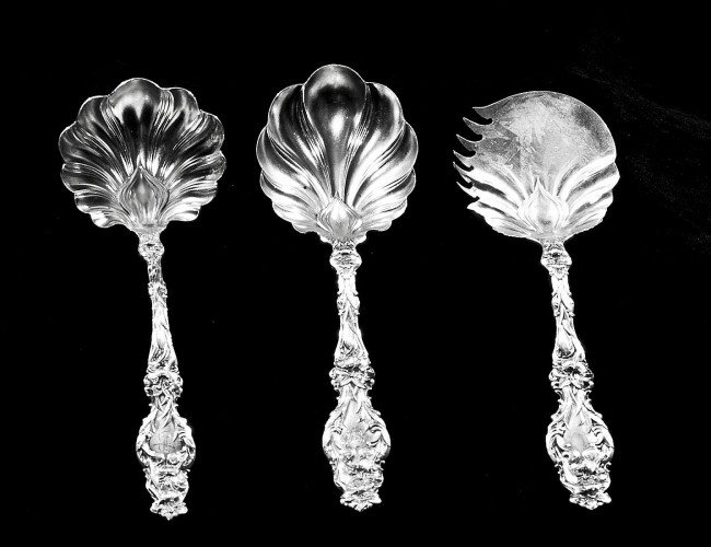 GROUP OF FIVE STERLING SILVER SERVING PIECES: American. Circa 1905. maker: Whiting. In the "Lily" pattern. Comprising: sauce ladle, two serving spoons and two fried oyster servers. (7 oz) (Monogrammed) (400/500)