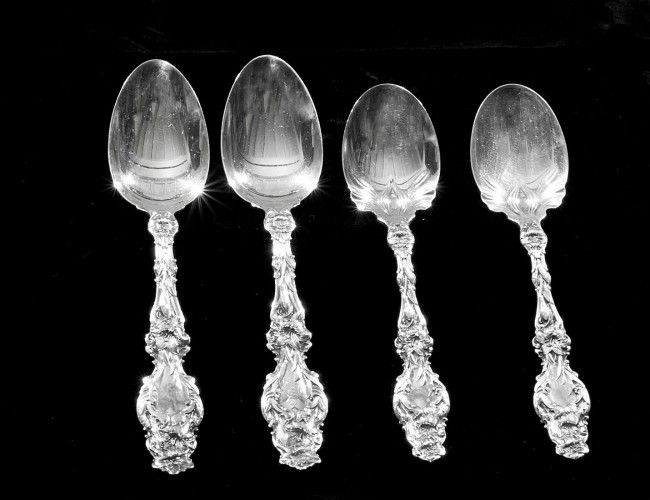 SET OF TWENTY-FOUR STERLING SILVER SPOONS: American. Circa 1905. Maker: Whiting. In the "Lily" pattern. Comprising: twelve tea spoons and twelve ice cream spoons. (20 oz) (Monogrammed) (500/600)