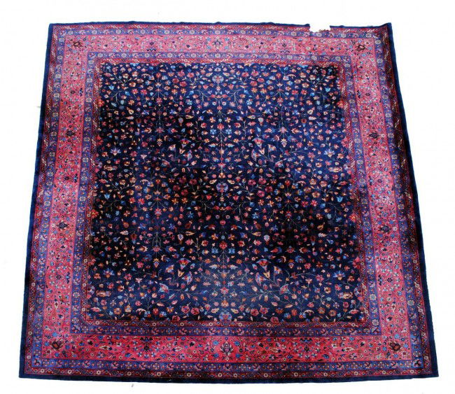 SEMI-ANTIQUE PERSIAN SAROUK CARPET: The dark blue field woven with flowering vines, enclosed by a dark rose main shah abbas border. Measuring 13'10" by 11'10". (Cond: damages and low areas) (1000/1500)