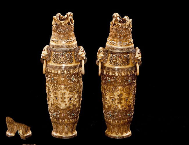 PAIR OF CARVED IVORY VASES AND COVERS: Chinese. Signed. Each tapering ovoid vessel with loose ring monster mask handles and archaic motif, set with semi-precious cabochon stones. Height 10 3/4". (3000/4000)