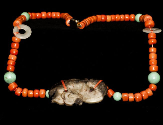 ARCHAIC FORM CARVED JADE PENDANT: Chinese. In the form of a recumbent foo dog suspended from a coral and jade bead necklace with a twelve karat gold filled clasp. Length 26". (250/350) NOTE: This lot is being re-offered for sale due t
