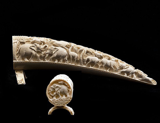 CARVED IVORY TUSK: Indian. Decorated with rows of various animals applied with a bridge stand. Length 12 ½". (400/500)