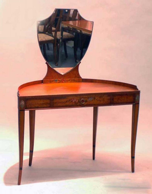 PAINTED AND INLAID SATINWOOD VANITY TABLE: American. 20th Century. By Irwin. The D-shaped top centered by a shield shape mirror above a frieze drawer, raised on ebony inlaid splayed legs ending in cuffs. Height 56". Width 42". Depth 19 3/8".