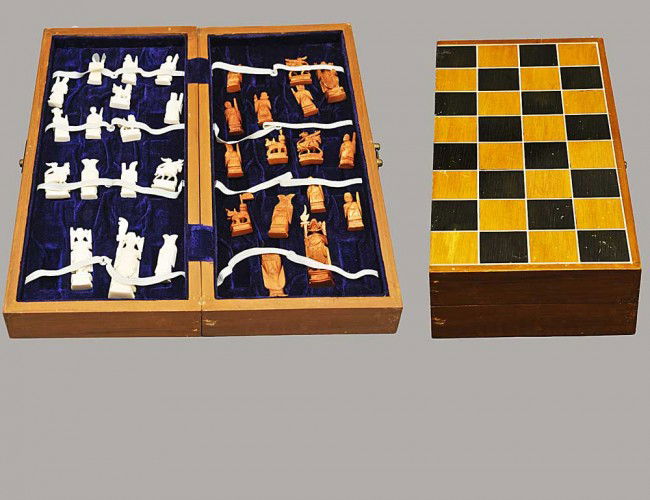 CARVED IVORY FIGURAL CHESS SET: Oriental. One side natural, the other stained. With board box. Height of king 3". (300/400)