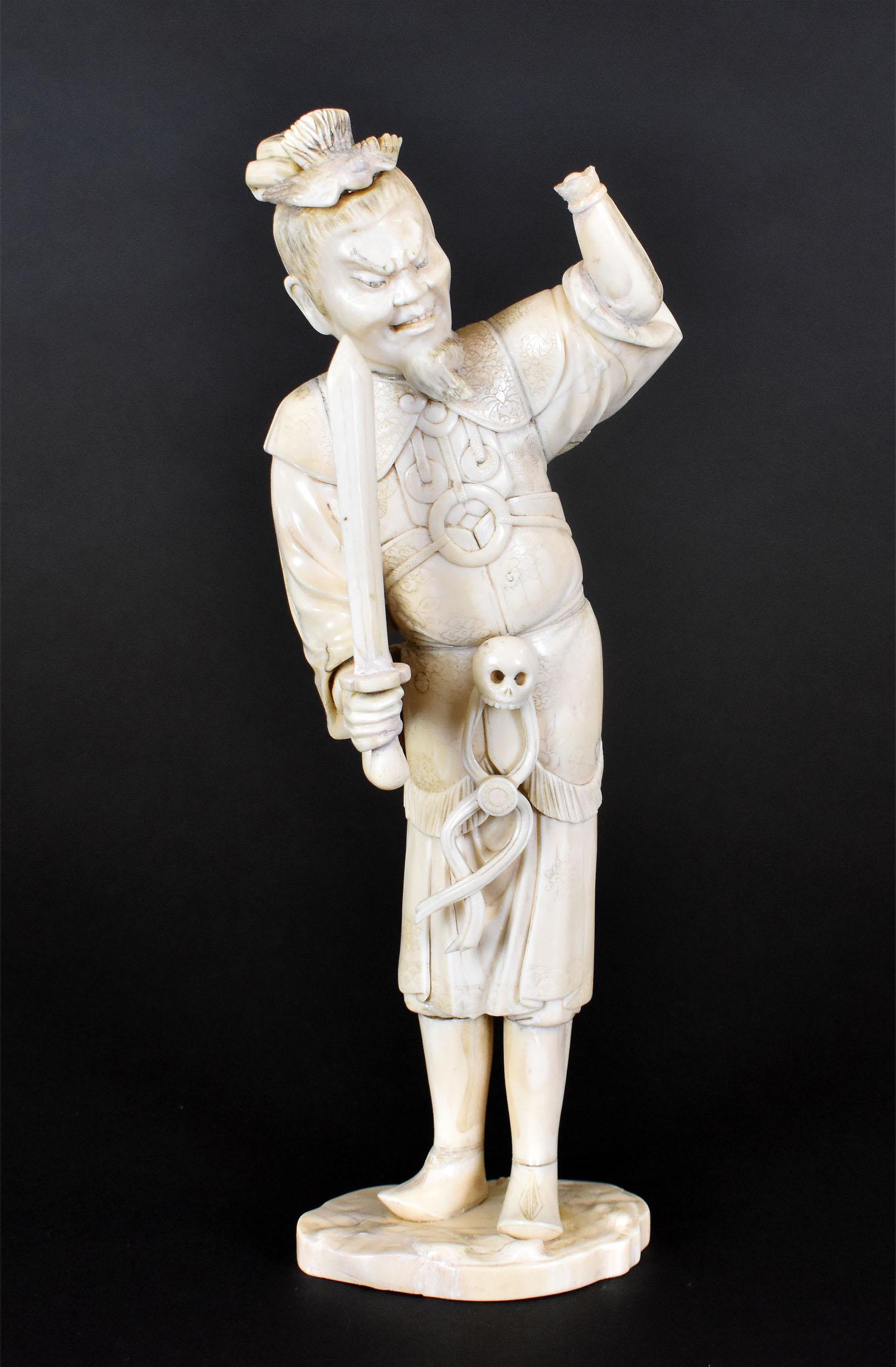CHINESE ZEALOT POISED TO SLAUGHTER A YOUNG DEMON: 19th Century. Signed on the underside. The bearded male figure with a bird atop his head and a skull tied about his waist, holds aloft in one arm a demon child, a sword poised to kill in the other. He