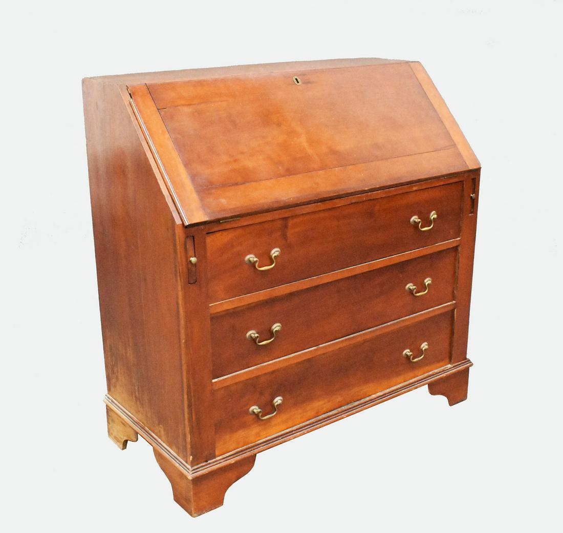 CHIPPENDALE CHERRYWOOD SLANT-FRONT DESK/CHEST OF DRAWERS: 19th Century. The hinged slant-front opening to a fitted interior above three long drawers, with brass bail handles, on bracket feet. Height 43.5 in., Width 42 in., Depth 20.5 in.