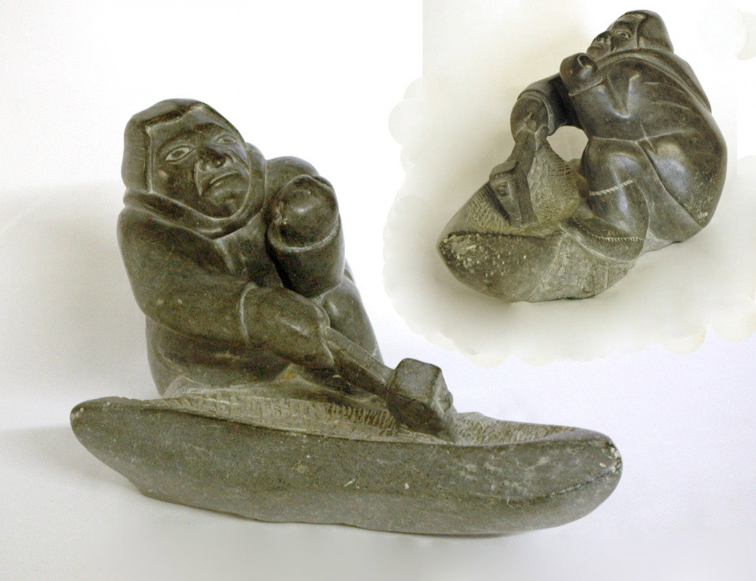 IMPRESSIVE CARVED STONE FIGURE OF AN INUK: Inuit. Signed and dated "ELI '84". The stooping figure carving a kayak with an axe. Length 12". Height 7 1/2". (800/1200)