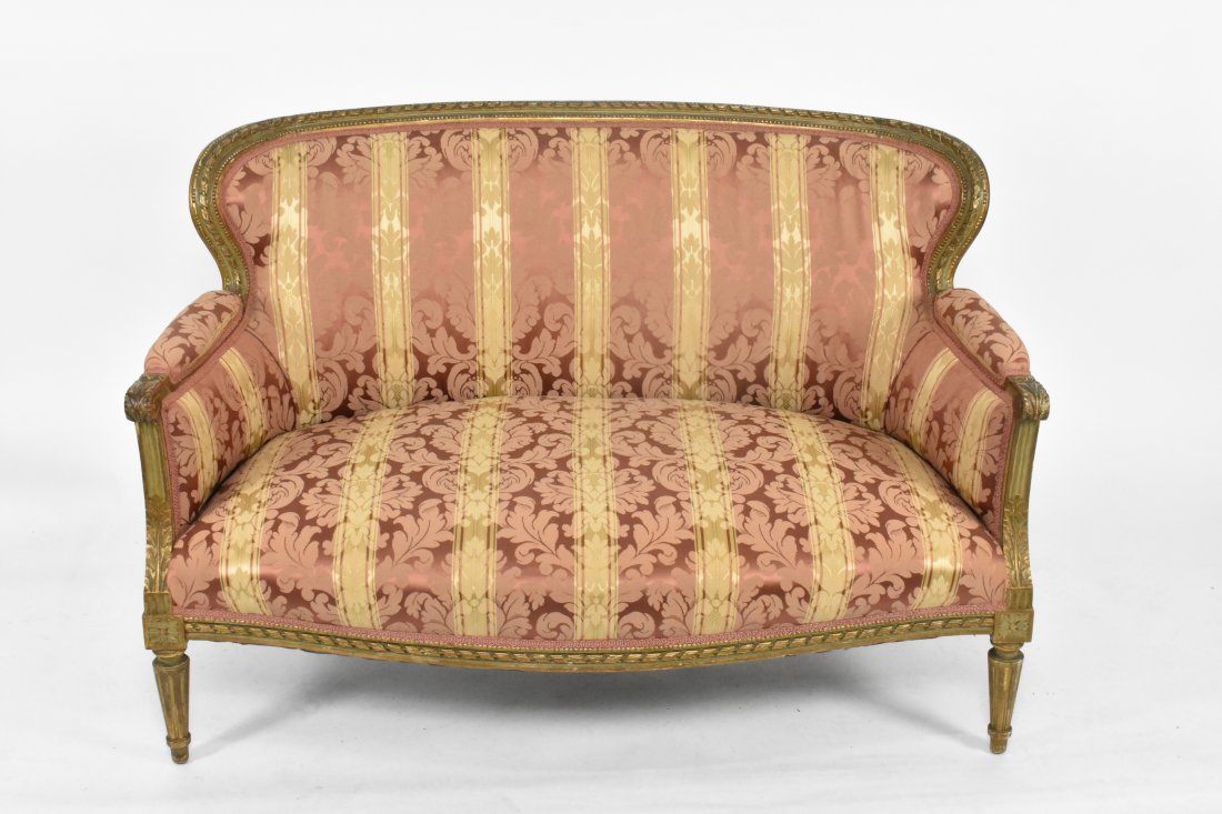 LOUIS XVI STYLE GILTWOOD SETTEE: The curved upholstered back with a carved twisted rope border, padded arms terminate into leaf handholds, the serpentine seat, on fluted tapered circular legs. Length 47 in. Height back to floor 33 in