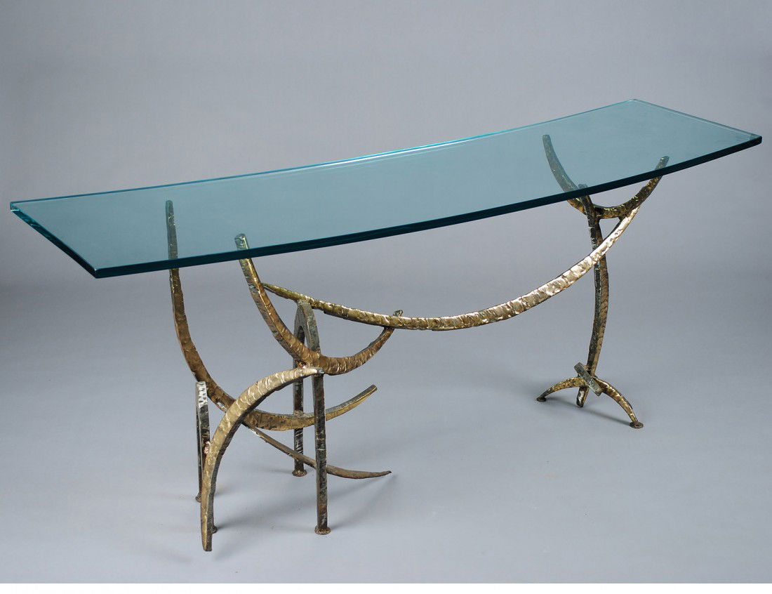 SILAS SEANDEL GILT BRONZE AND GLASS CONSOLE TABLE: Signed and No. 3/9. The oval beveled glass supported by the hammered bronze base. Height 28 1/4". Width 70". Depth 18 1/4". (500/700)