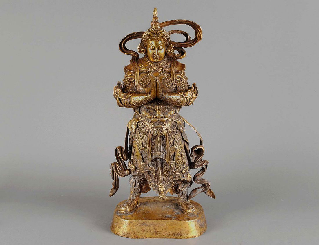 RARE AND LARGE GILT BRONZE FIGURE OF A GUARDIAN: Chinese. Ming Dynasty. 16th Century. Cast in a standing position, wearing full armur with hands held together. (15000/20000)