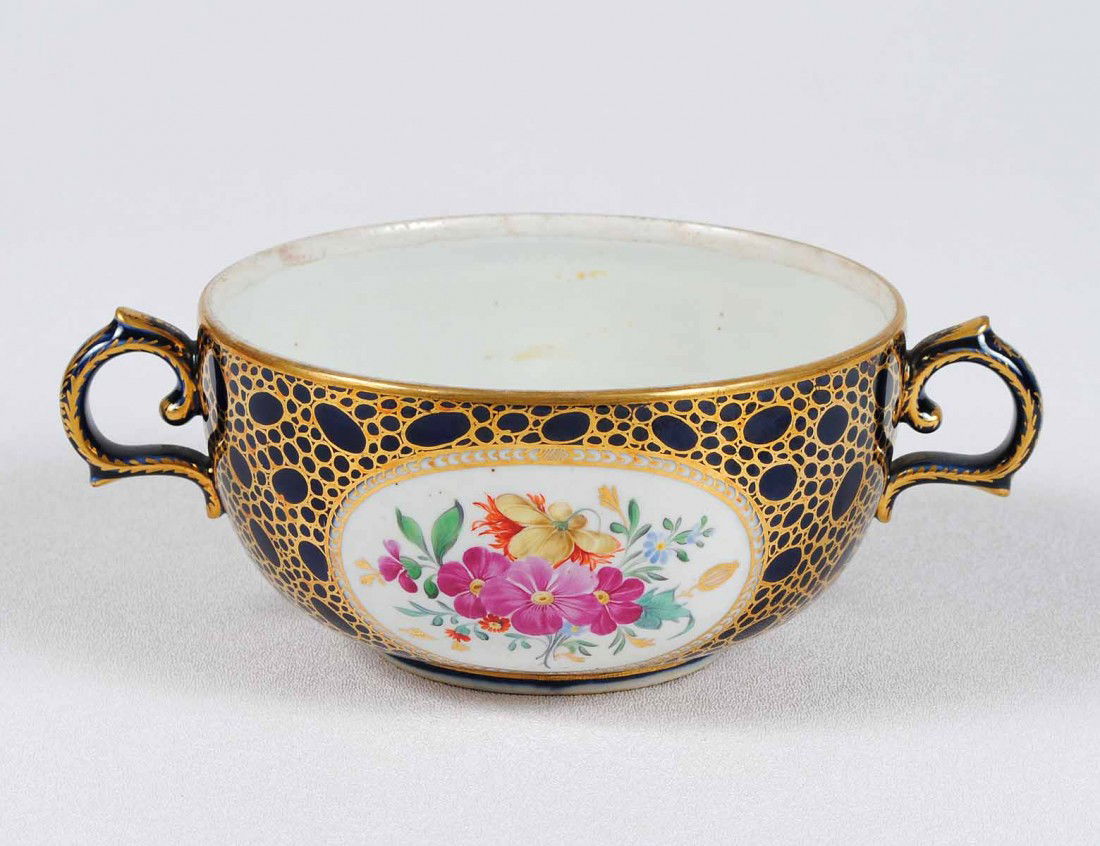 MEISSEN PORCELAIN TWIN HANDLED CUP: German. 19th Century. Underglaze blue crossed swords. Painted with floral panels on a blue ground with gilt highlights. Diameter 5 1/2". (125/175)