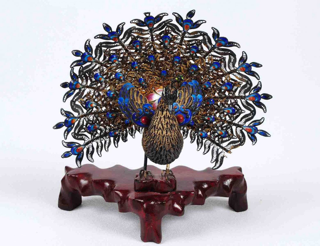 SILVER GILT FILIGREE AND ENAMEL FIGURE OF A PEACOC: Chinese. Modeled with open tail feathers. Height 5 ¼". Raised on a wooden stand. (Cond: minor loss to a blossom) (250/350)